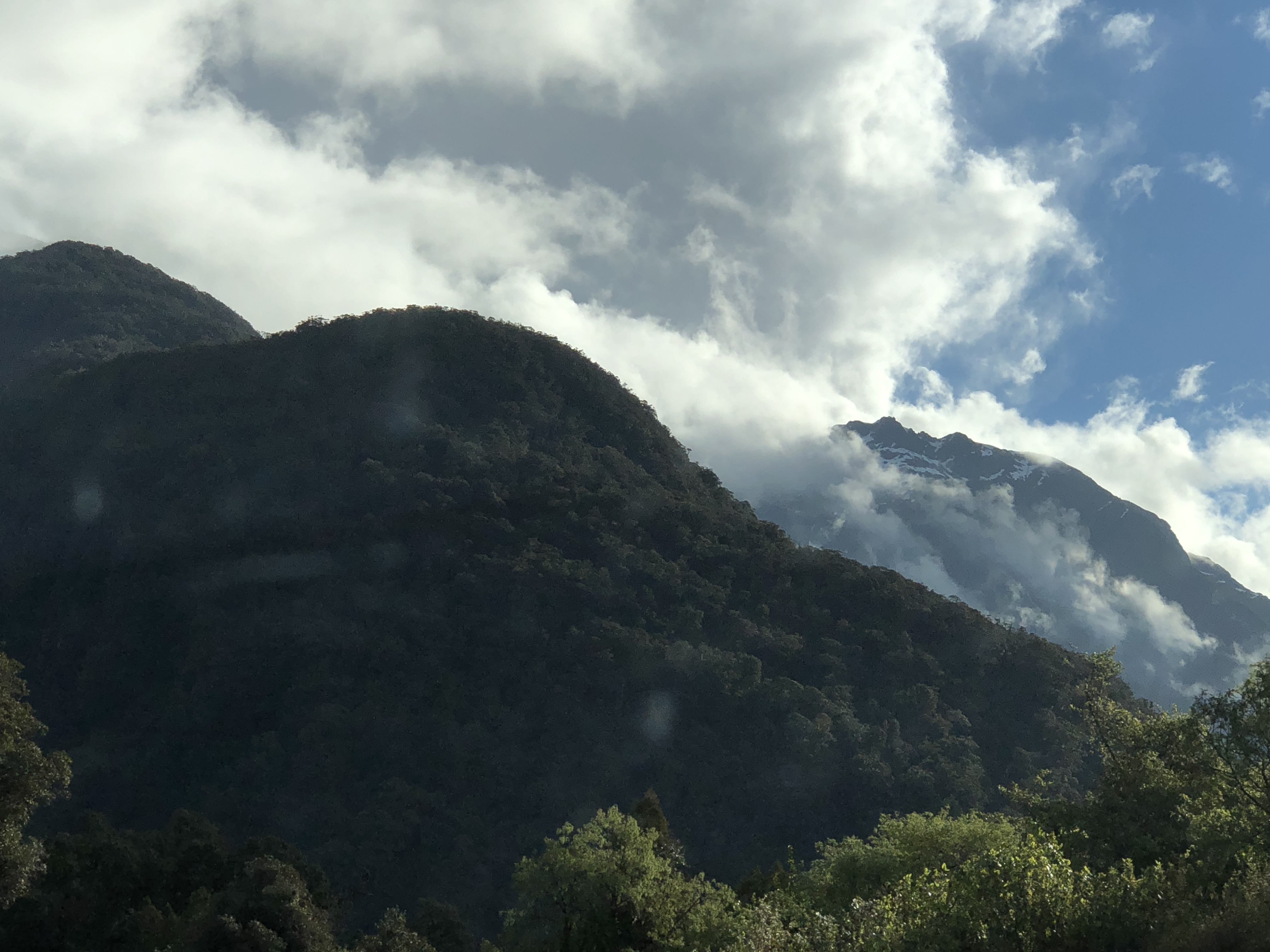 NZ, mountains w trees, snow layers, clouds