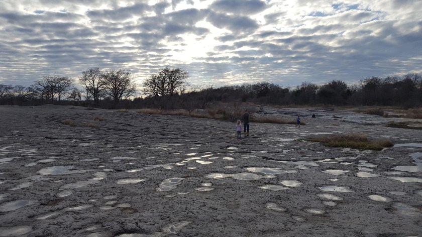 mckinney falls, guthrie w children on rock bed w spotted sky