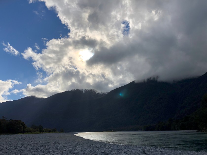 NZ, beach w snow-topped mountains, sun in clouds