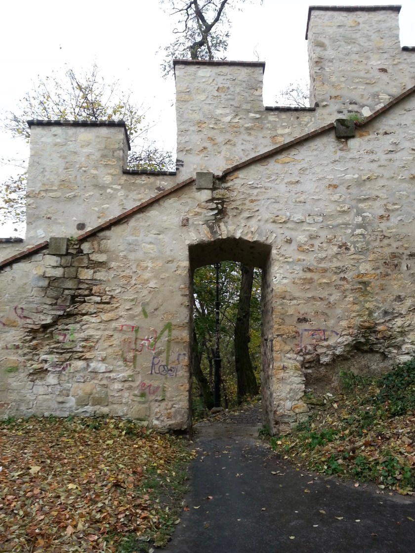 Doorway thu old white stone wall into woods, Switzerland