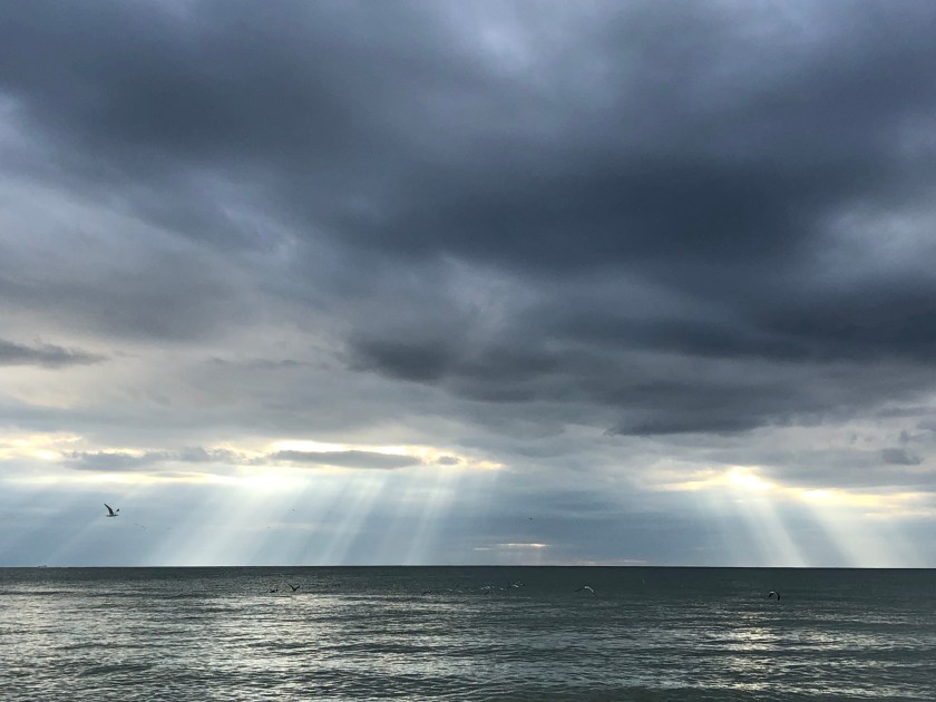 Sun rays and rain from storm clouds, w gull, over Gulf