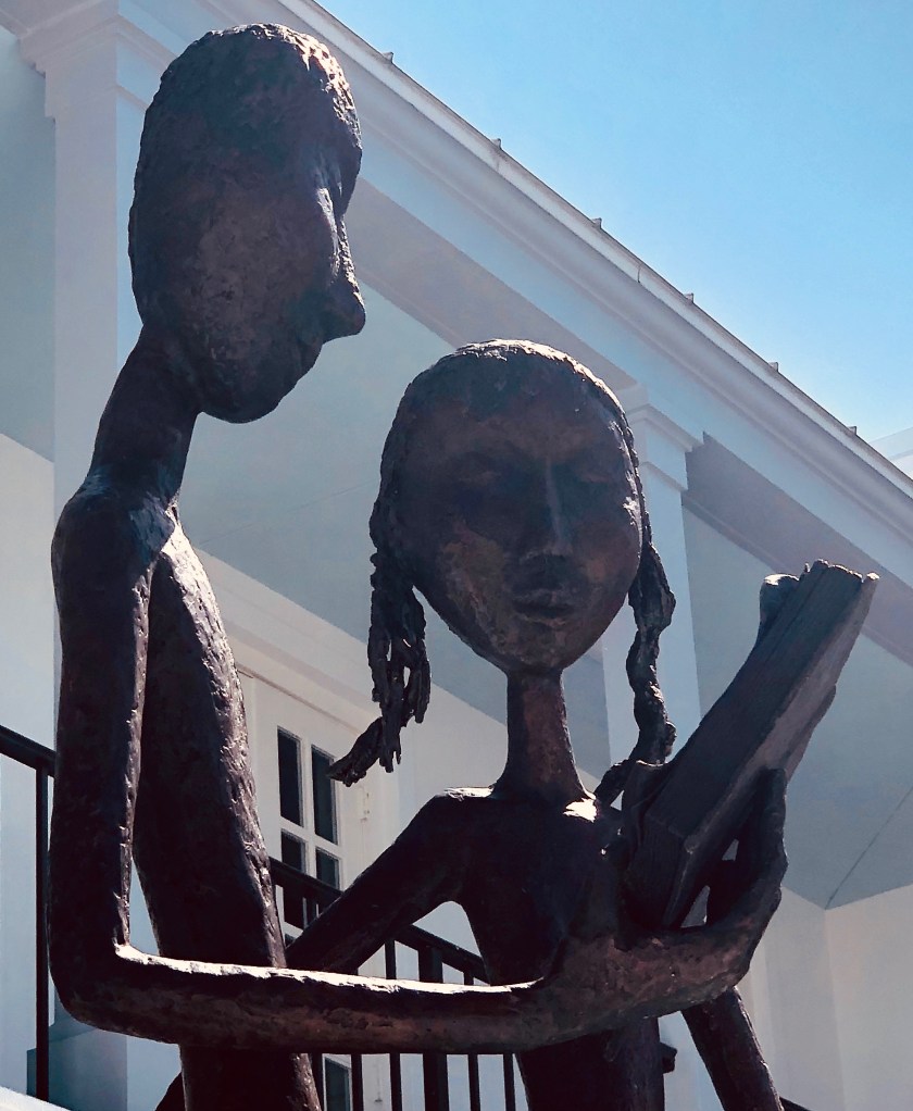 Bronze sculpture, man reading to woman